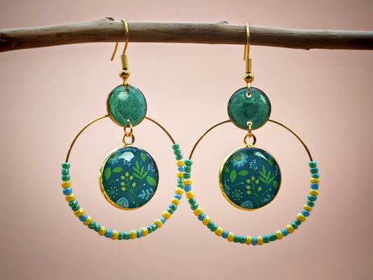 Boucles d’oreilles – Créoles dorées & feuillage vert sur fond bleu profond
