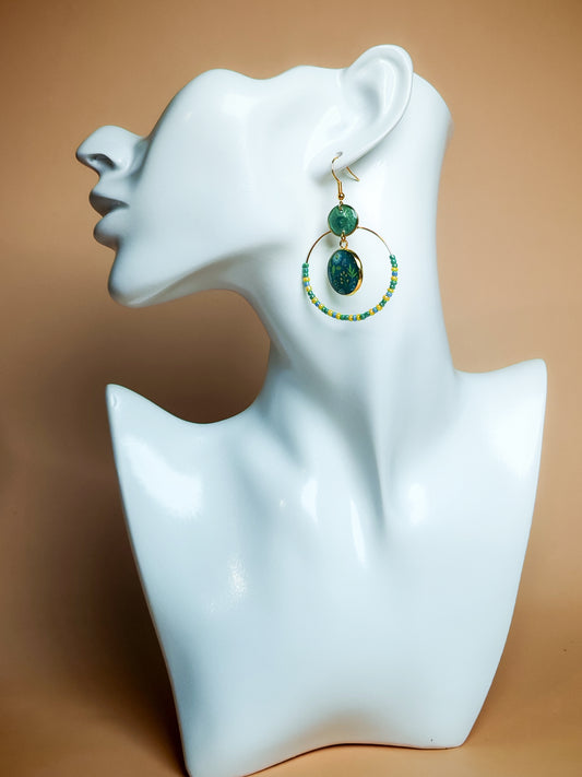 Boucles d’oreilles – Créoles dorées & feuillage vert sur fond bleu profond