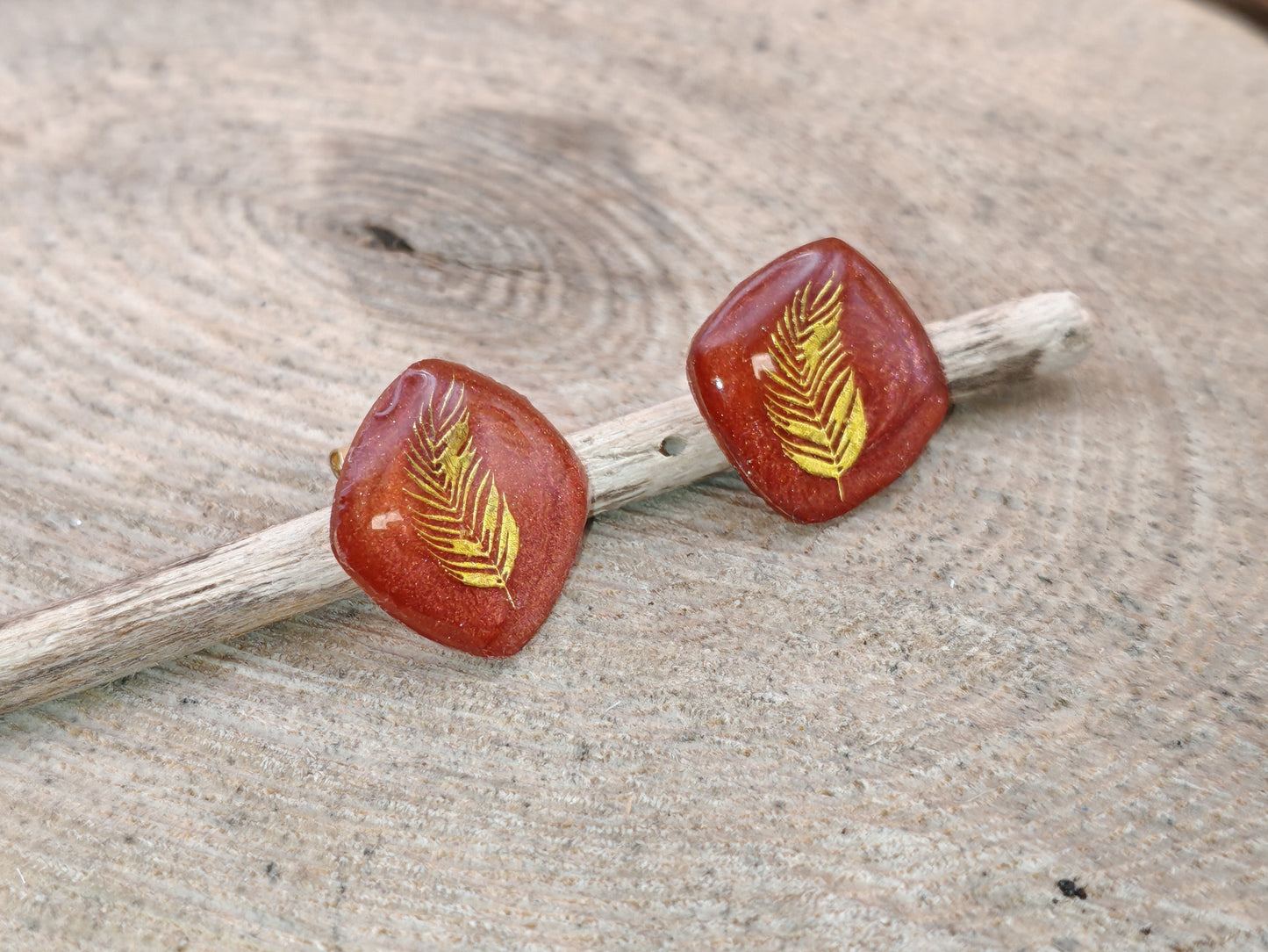 Clous d’oreille – Plume dorée sur résine rouge profonde
