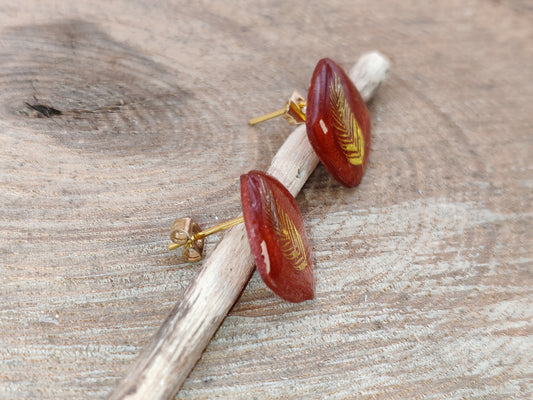 Clous d’oreille – Plume dorée sur résine rouge profonde